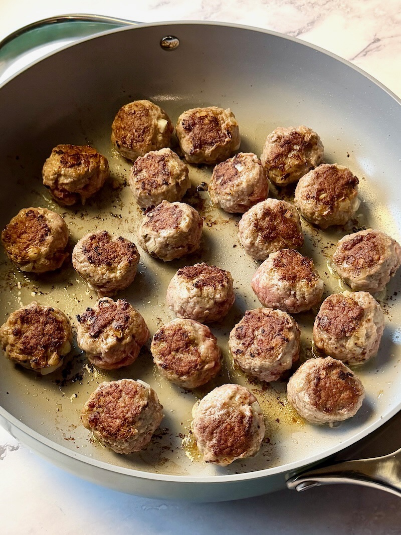 Meatballs browned in a skillet.