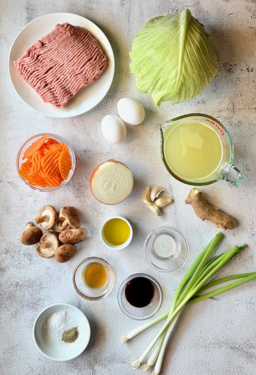 Ingredients displayed for egg roll soup. Ground turkey, onions, garlic, ginger, green cabbage, eggs, carrots, shiitake mushrooms, chicken broth, soy sauce, sesame oil, avocado oil, rice vinegar, green onions, salt and pepper. 