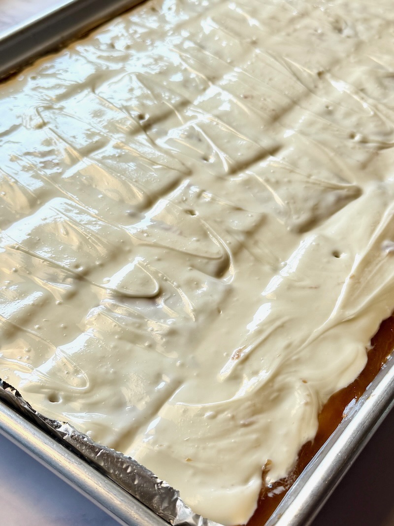 Melted white chocolate spread over crackers.