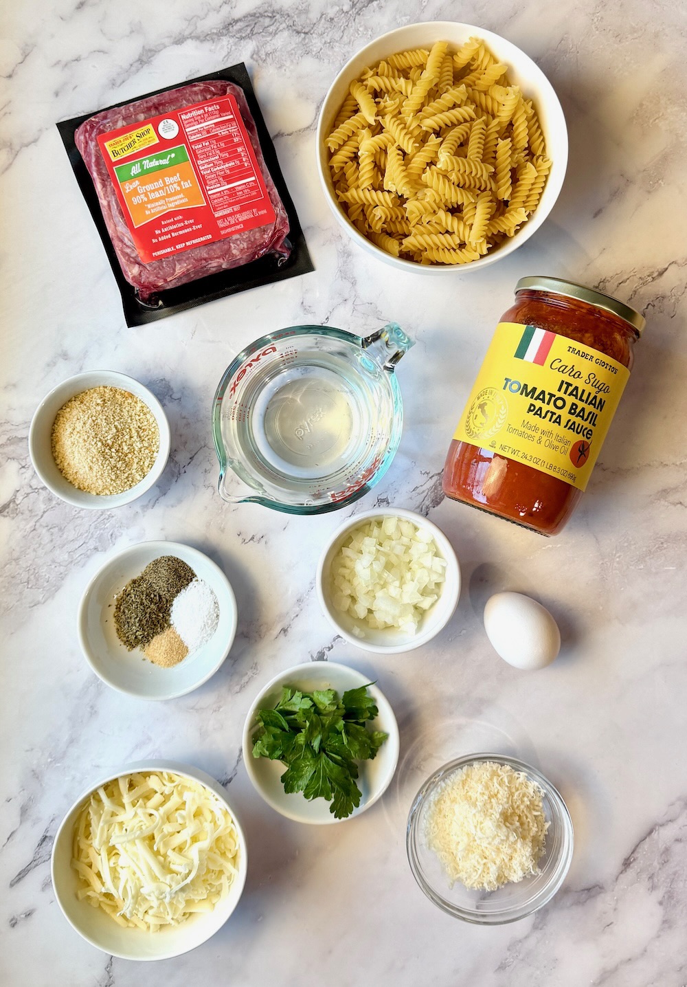 Ingredients listed for Italian Meatball Casserole. Ground beef, rotini pasta, bread crumbs, water, pasta sauce, seasonings, onion, egg, parsley, mozzarella and parmesan cheese. 