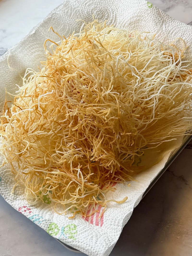 Fried rice noodles on a plate lined with paper towels for Chinese chicken salad