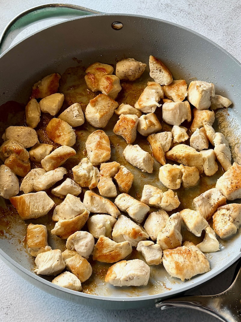 Chicken pieces browned in a skillet.
