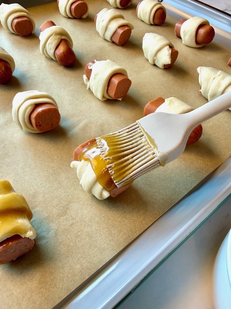 Glaze brushed on pigs in a blanket.