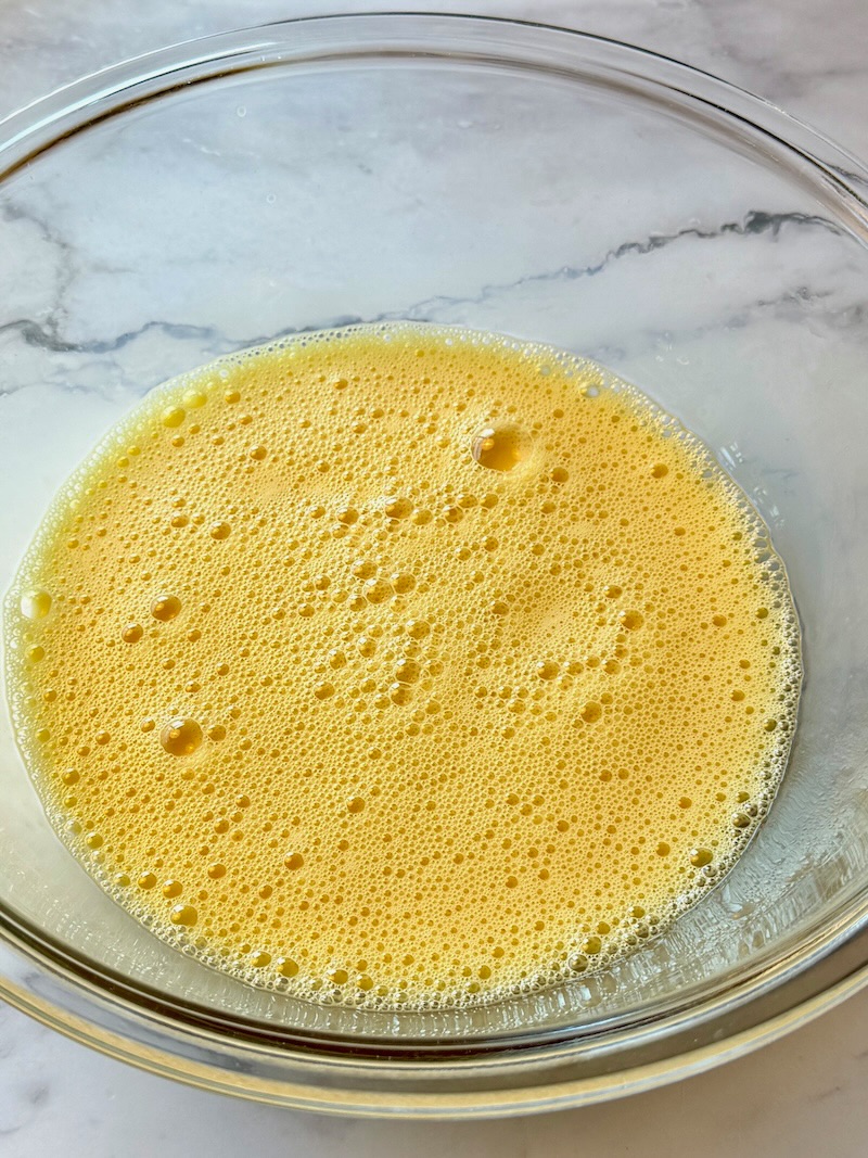 Eggs lightly beaten in a mixing bowl with milk. 