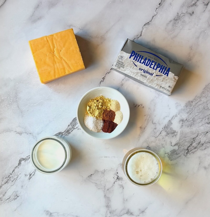 Ingredients displayed for crockpot beer cheese dip. Cream cheese, sharp cheddar cheese, spices, half and half, light beer. 