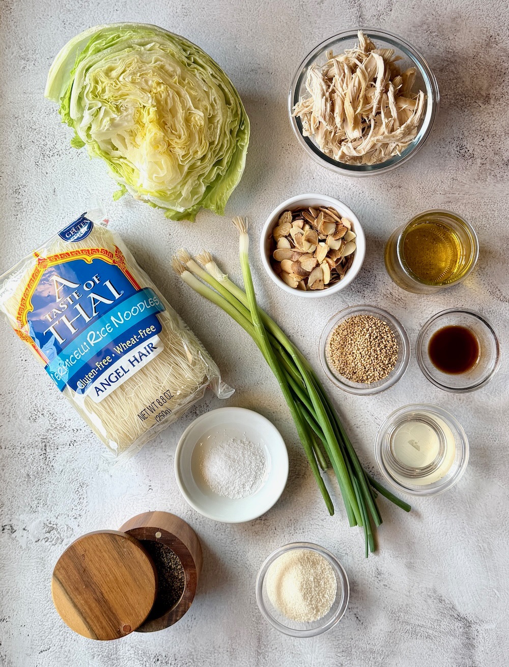 Ingredients displayed for Mom's Chinese chicken salad. Iceberg lettuce, shredded cooked chicken, green onions, vermicelli rice noodles, toasted almonds, toasted sesame seeds, avocado oil, soy sauce, sugar, vinegar, salt, ground black pepper.