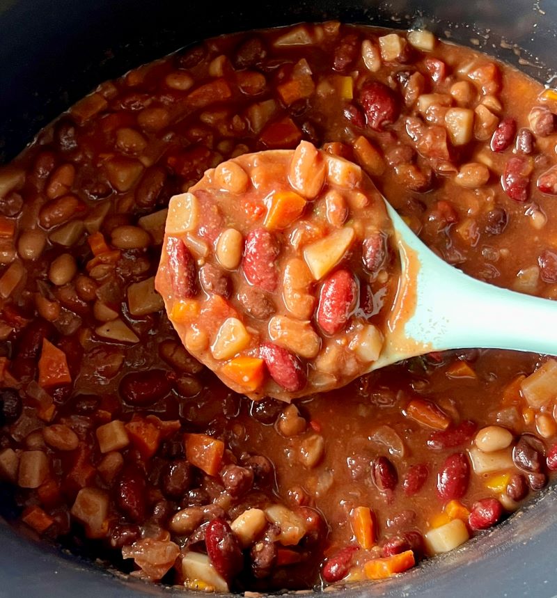 Pot of chili ladled with a spoon.