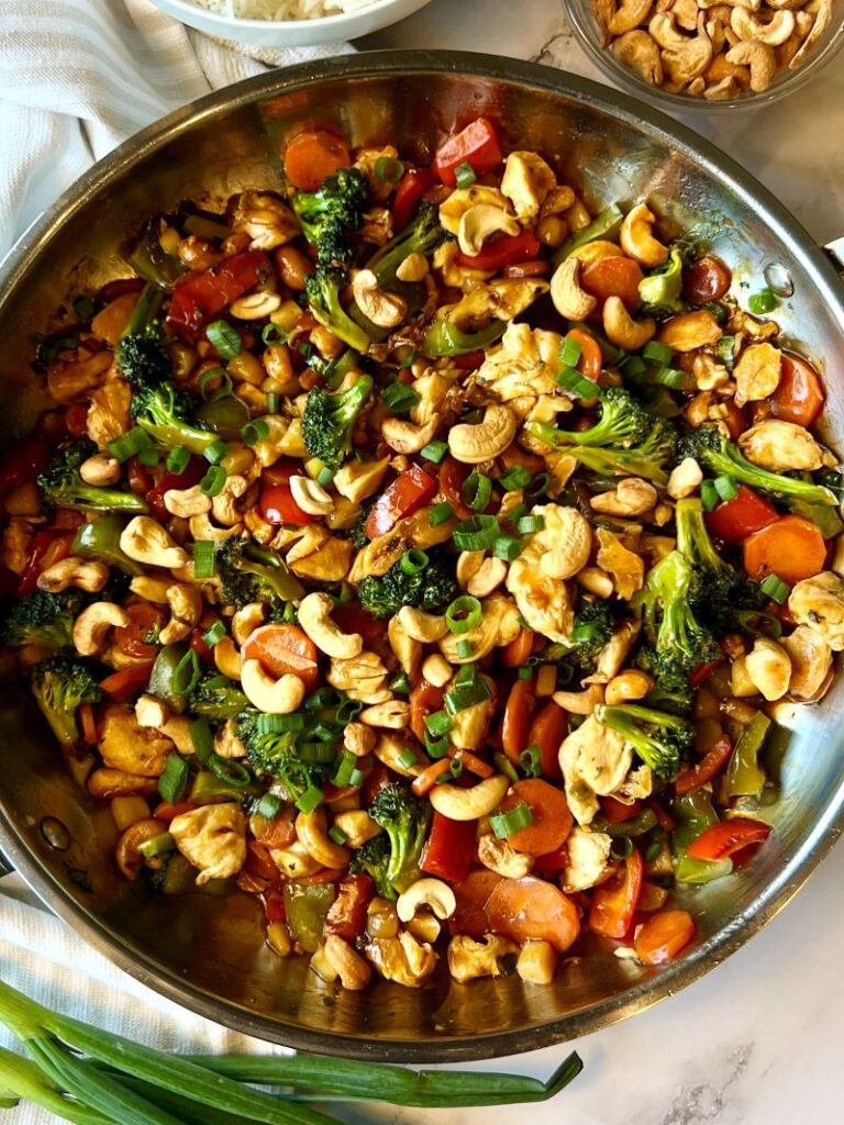 A skillet with cashew chicken and veggies.