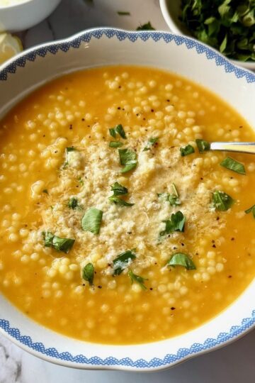 Italian pastina soup in a bowl with fresh parmesan and parsley.