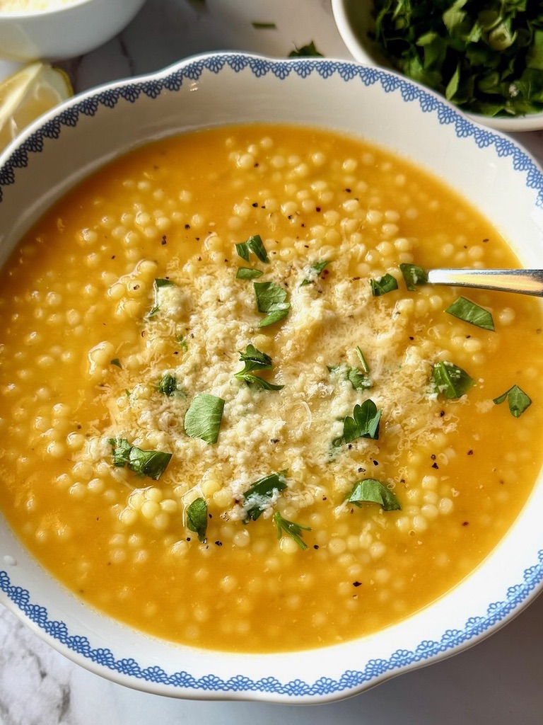 Italian pastina soup in a bowl with fresh parmesan and parsley.