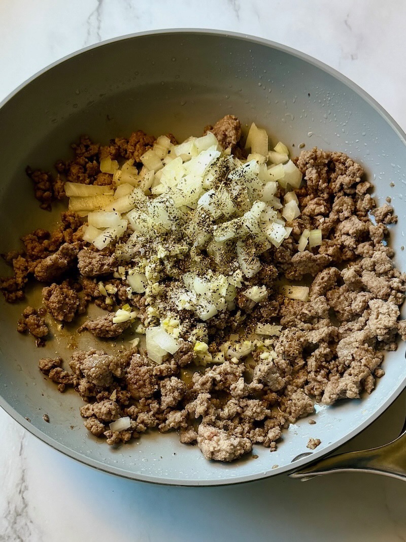 Ground beef and onions cooked in a skillet.