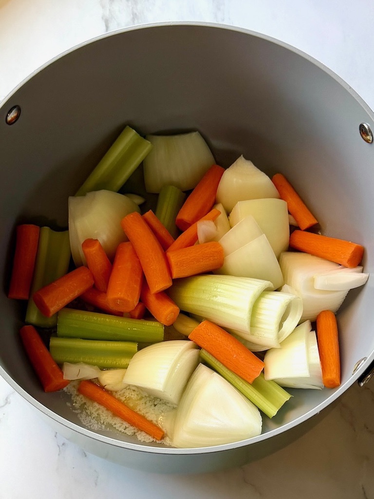 Raw vegetables in a soup pot with butter, salt and pepper
