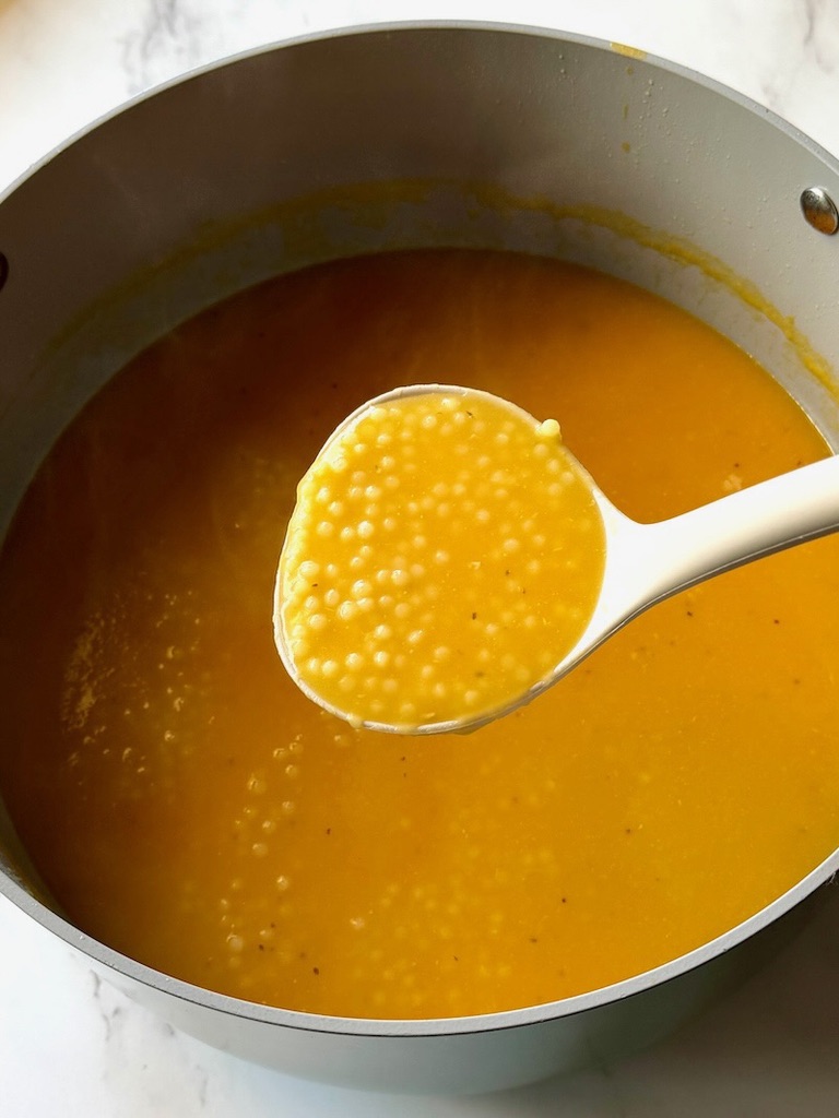 Pastina Soup cooked in a soup pot with a ladle. 