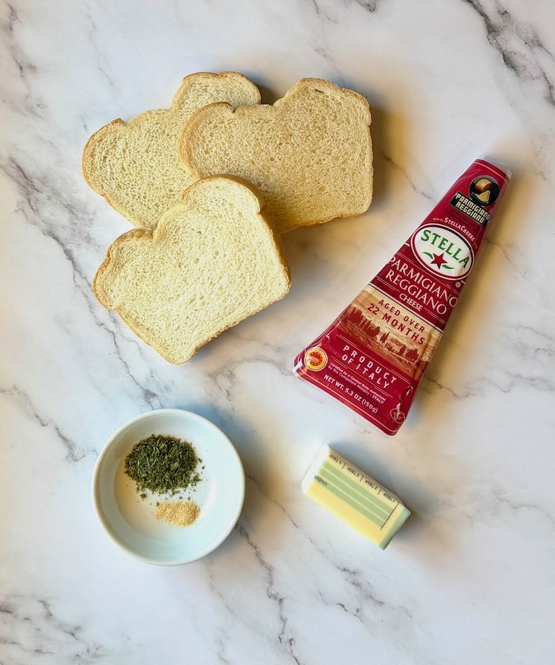 Ingredients displayed for crispy parmesan toast. Thick white bread, fresh parmesan, butter, garlic powder, dried parsley. 
