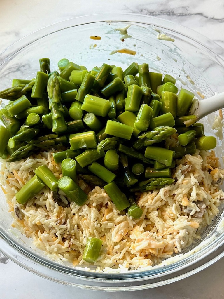 Asparagus added to the rice mixture in a bowl.