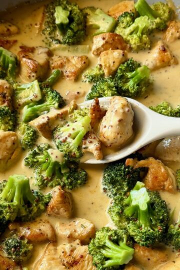 Creamy Honey Mustard Chicken and Broccoli in a skillet with a serving spoon,