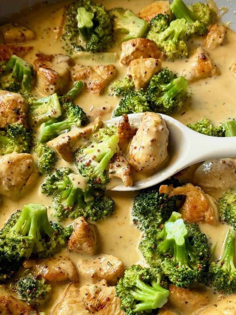 Creamy Honey Mustard Chicken and Broccoli in a skillet with a serving spoon,