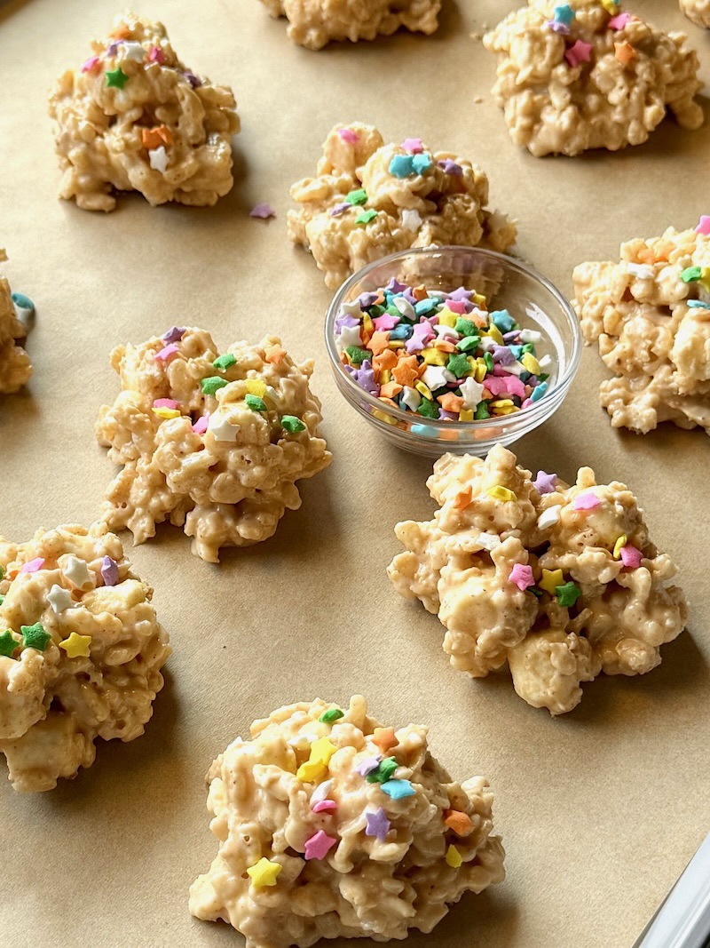 Avalanche cookies on a sheet pan with a small bowl of sprinkles
