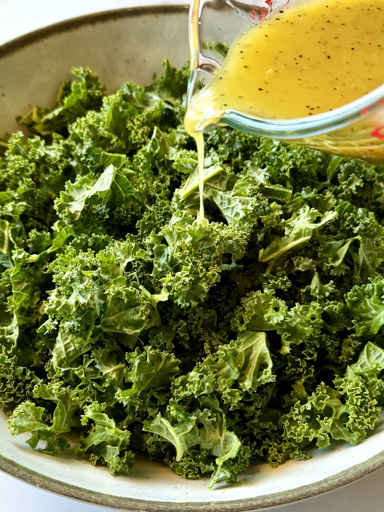 Dressing drizzled over the kale to help massage it.