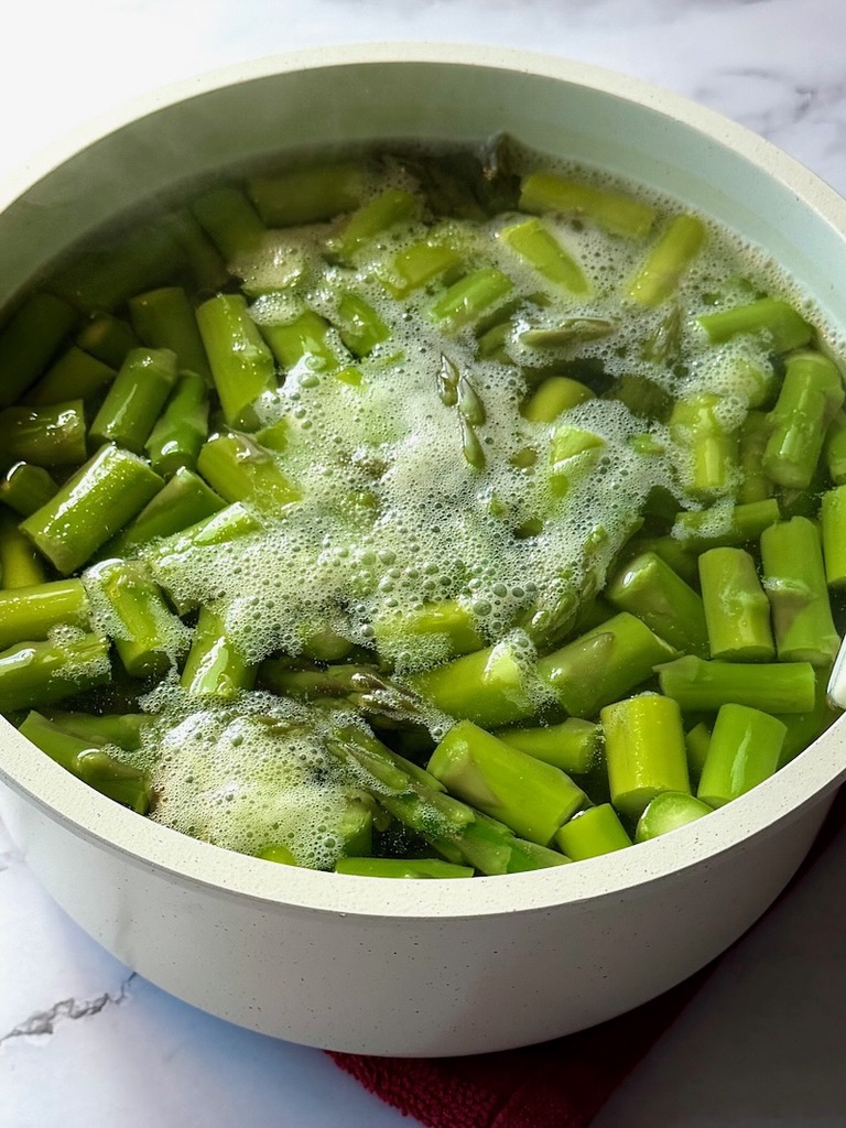 Blanching asparagus in a small pot with boiling water.