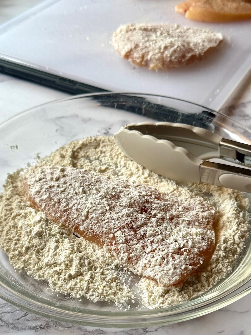Chicken dredged in flour and parmesan cheese.
