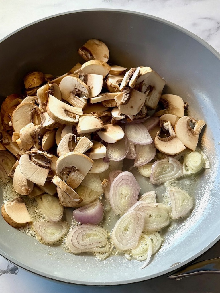 Shallots and mushrooms sautéed in a skillet with butter and oil. 