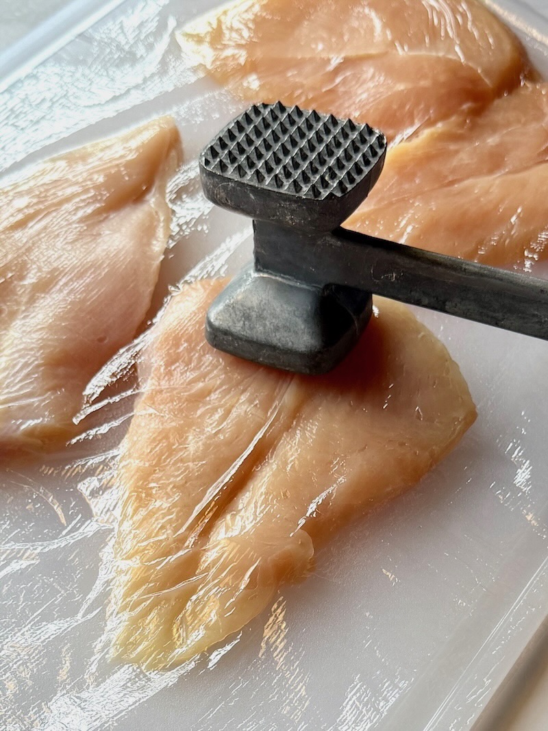 Using a meat mallet to pound chicken so all pieces are even in thickness. 