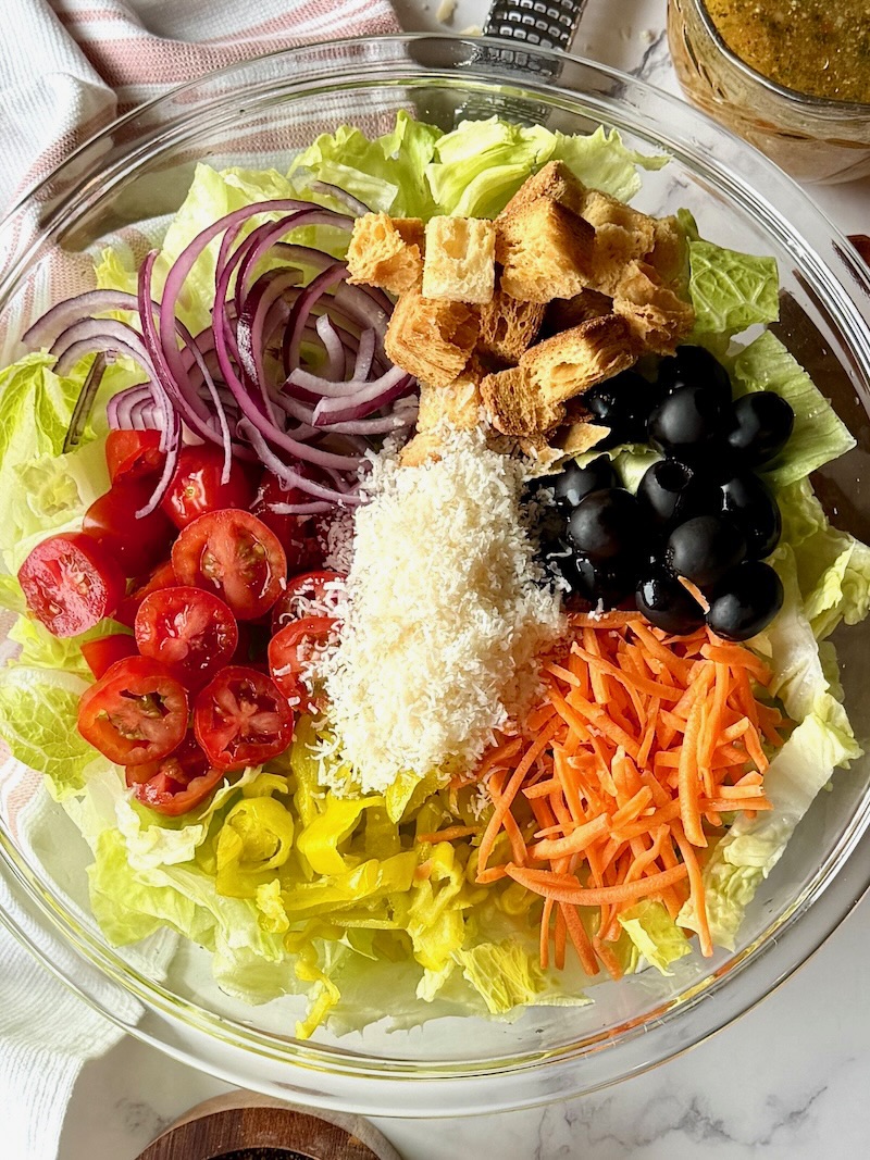 Olive garden salad ingredients in a serving bowl in sections 