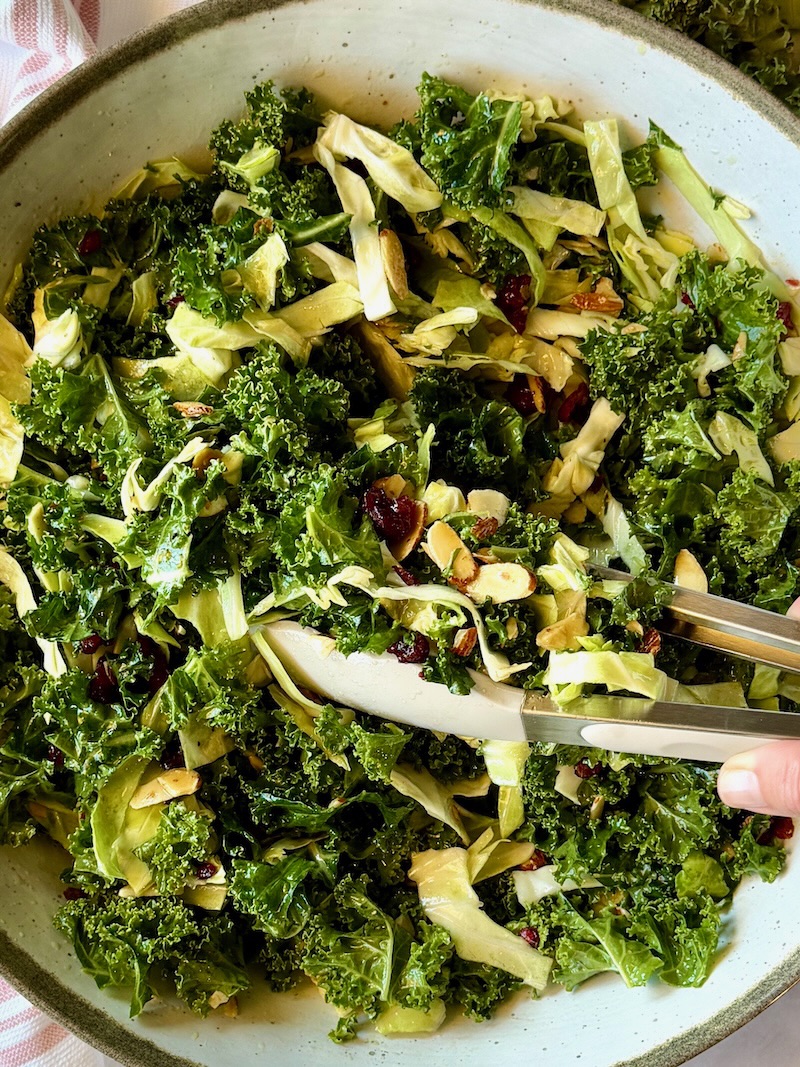 kale crunch salad in a serving bowl with tongs