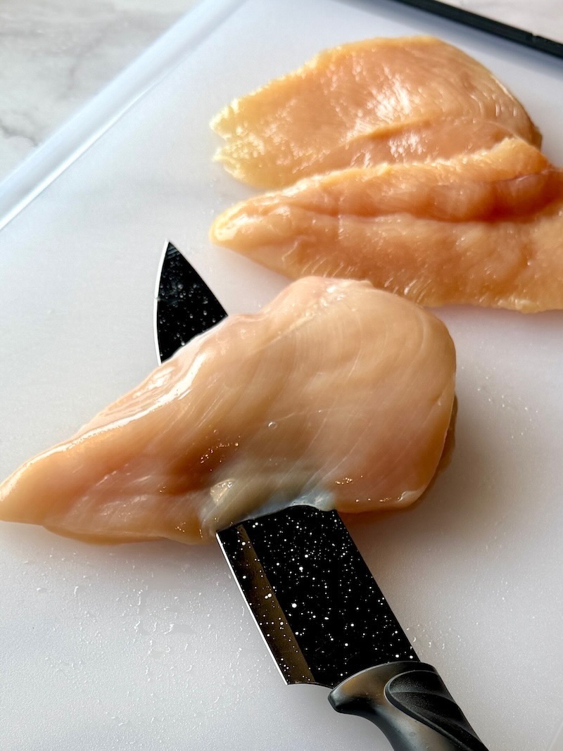 Slicing chicken breast in half horizontally. 