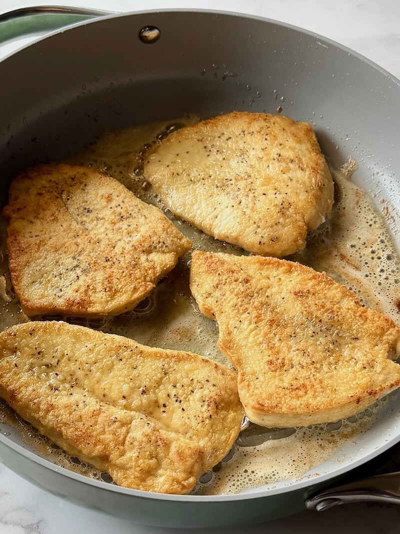 Chicken browned in a skillet with butter and olive oil. 