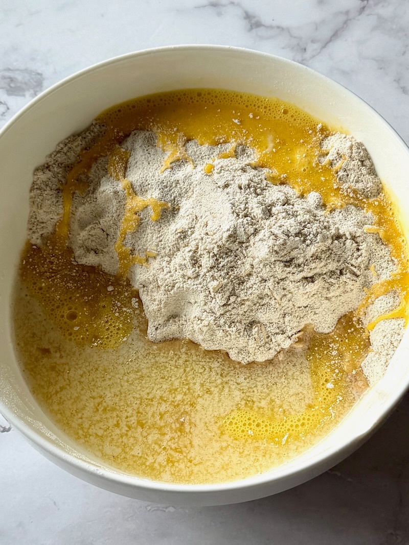 melted butter and egg added to the dry ingredients in a bowl.