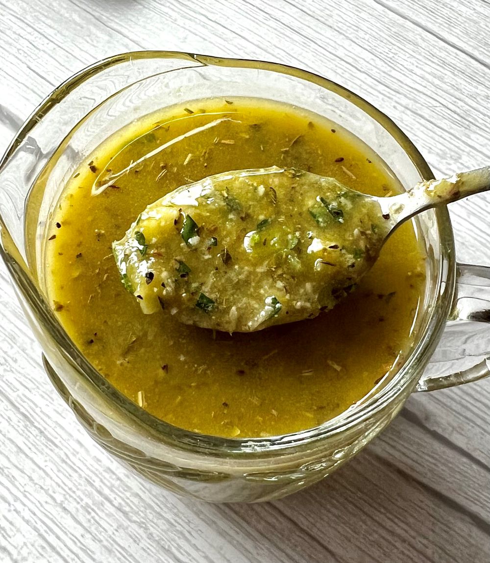 Homemade Italian dressing combined in a small bowl with a spoon.