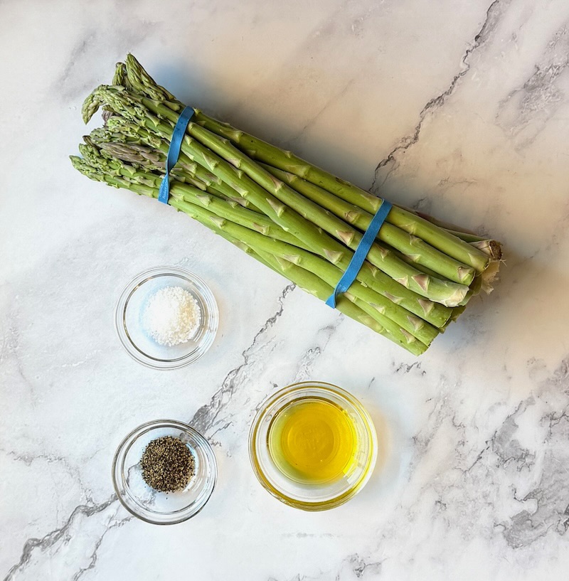 Ingredients displayed for roasted asparagus. Fresh asparagus, olive oil, salt and pepper.