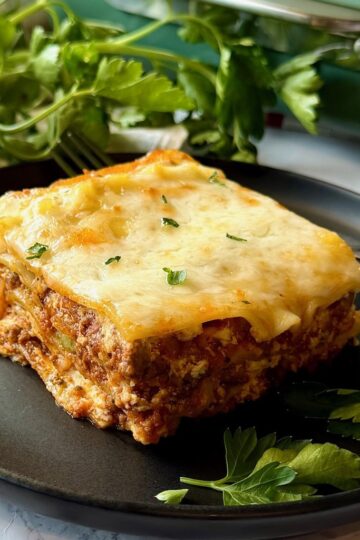 Sour cream lasagna sliced on a serving plate with fresh parsley