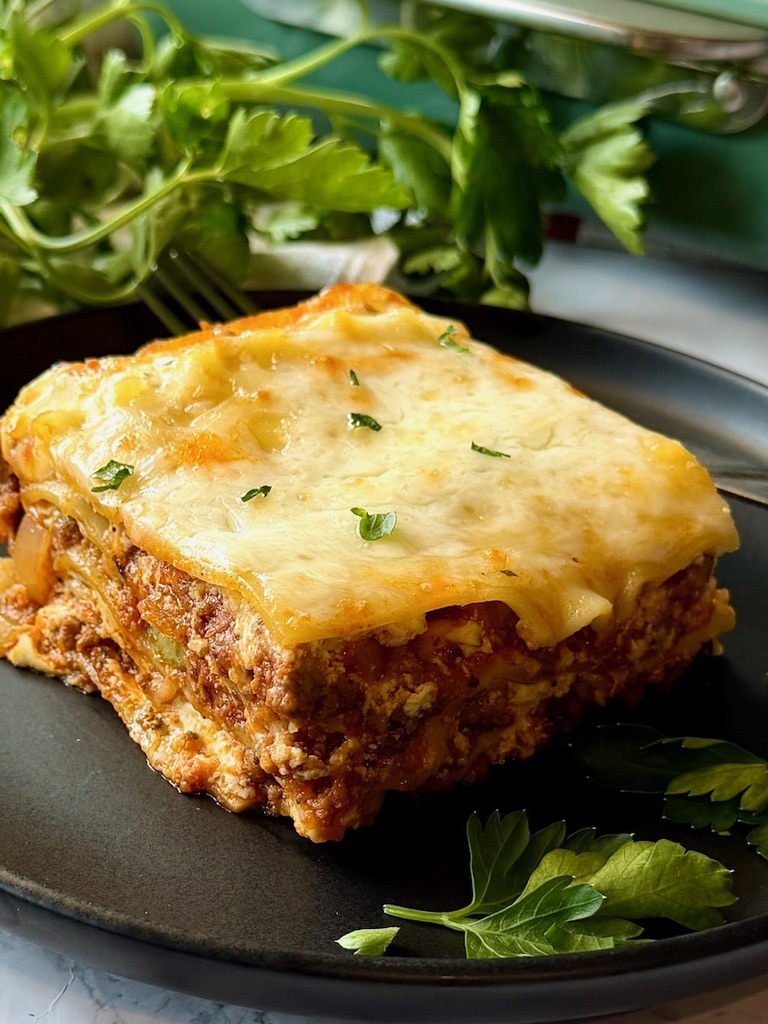 Sour cream lasagna sliced on a serving plate with fresh parsley