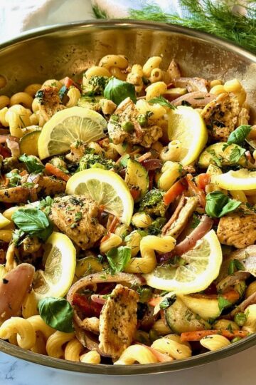 Chicken Primavera in a skillet with lemon slices on top