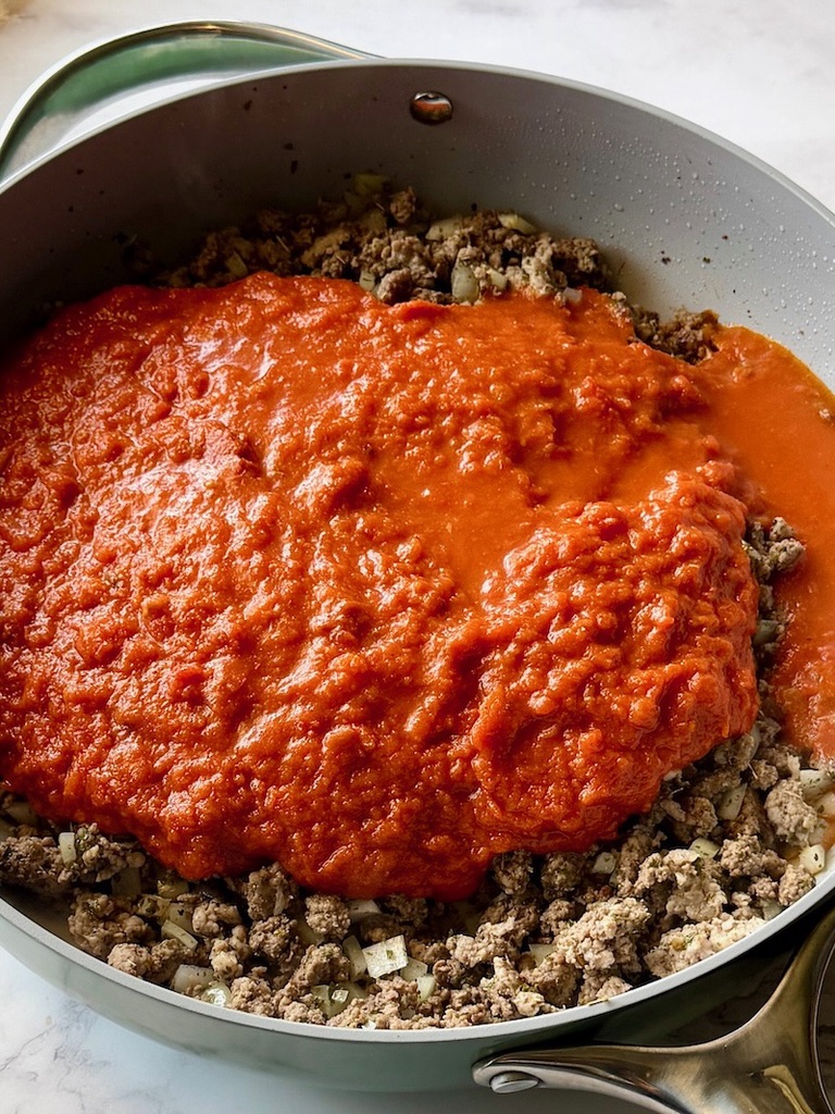 Pasta sauce added to the skillet with ground meat