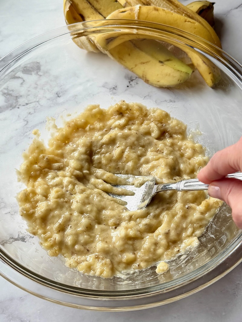 Bananas mashed in a bowl with a fork