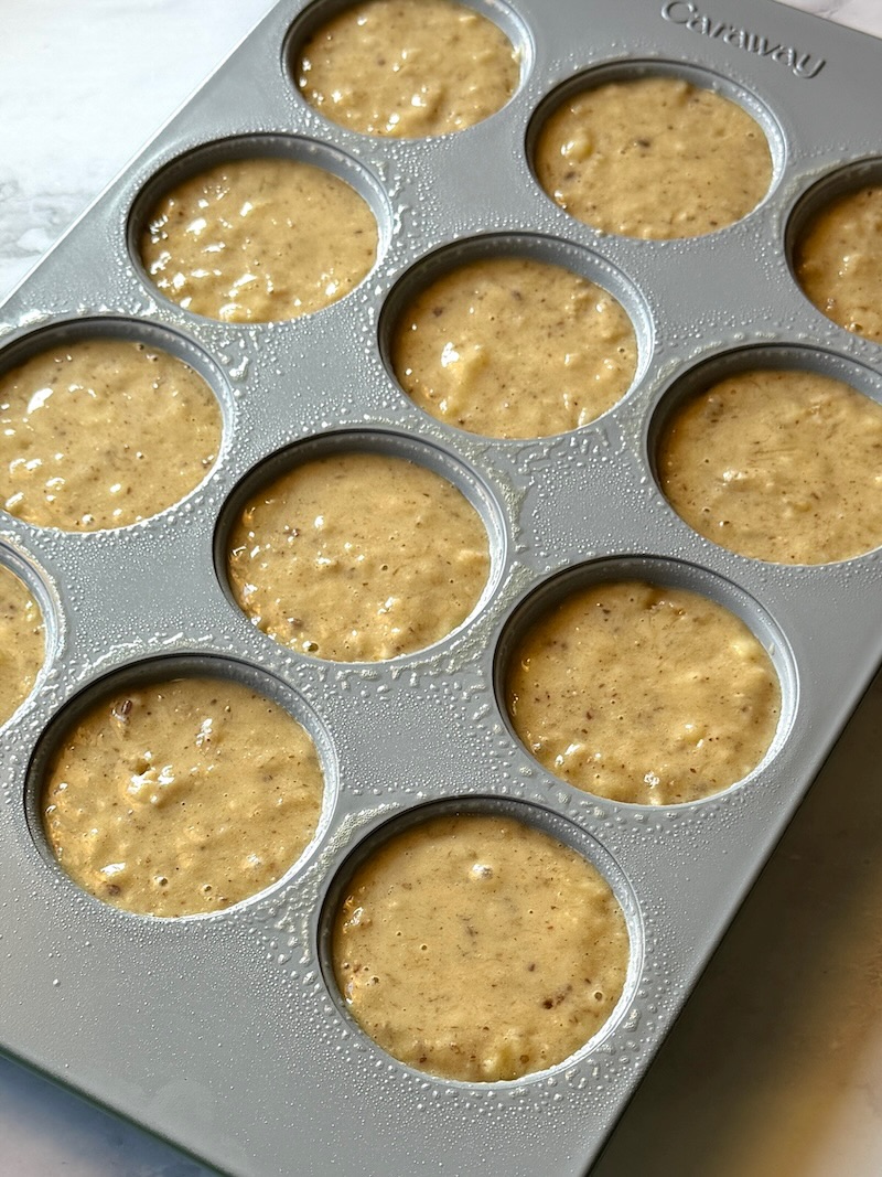 Muffin batter portioned in a muffin pan.