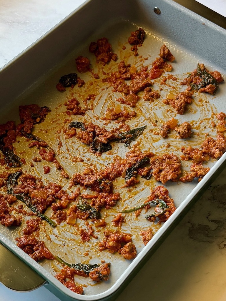 Small portion of meat sauce in the bottom of a baking dish