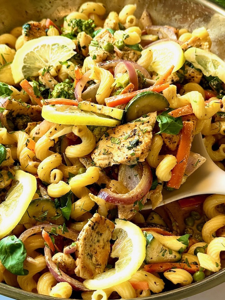 Chicken primavera in a skillet with a serving spoon