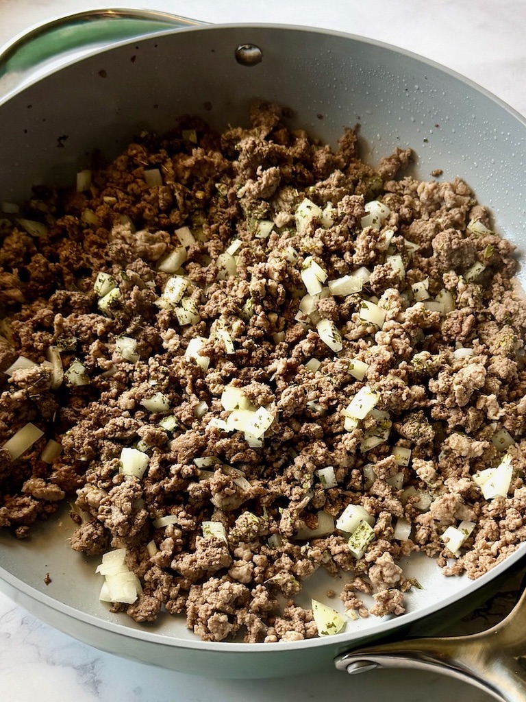 Ground beef, sausage, onions, and garlic cooked in a skillet. 