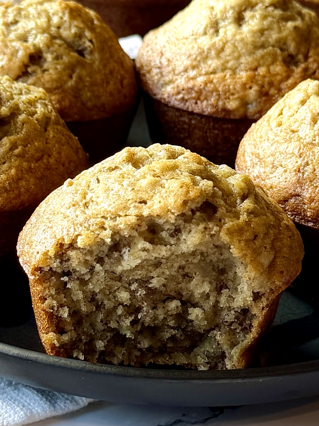 Close up of a fluffy banana muffin with a bite taken out of it to show the fluffy inside,