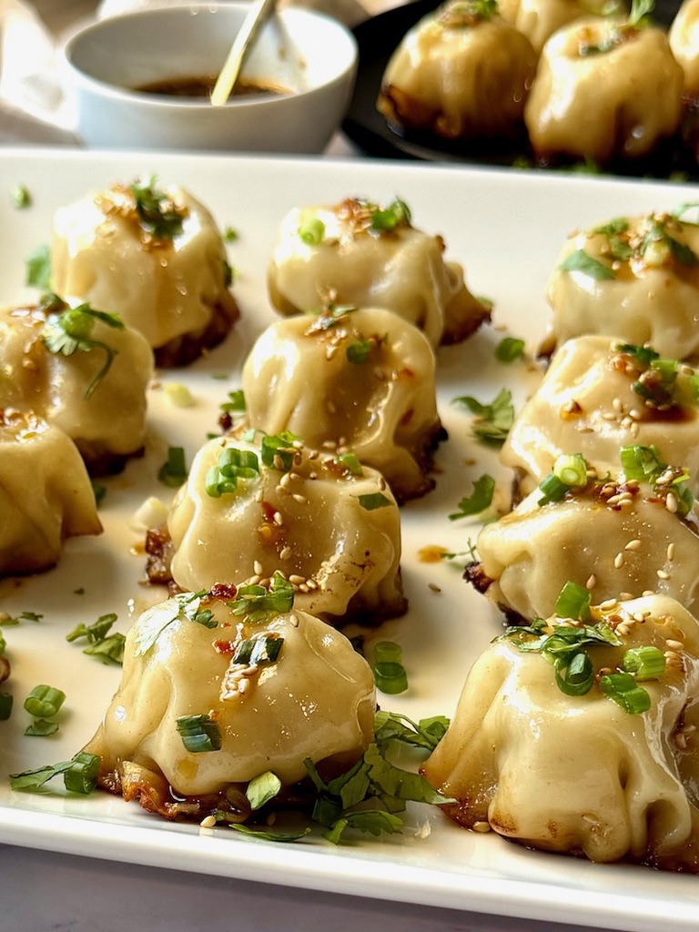 No fold chicken dumplings on a serving plate with green onions and cilantro.