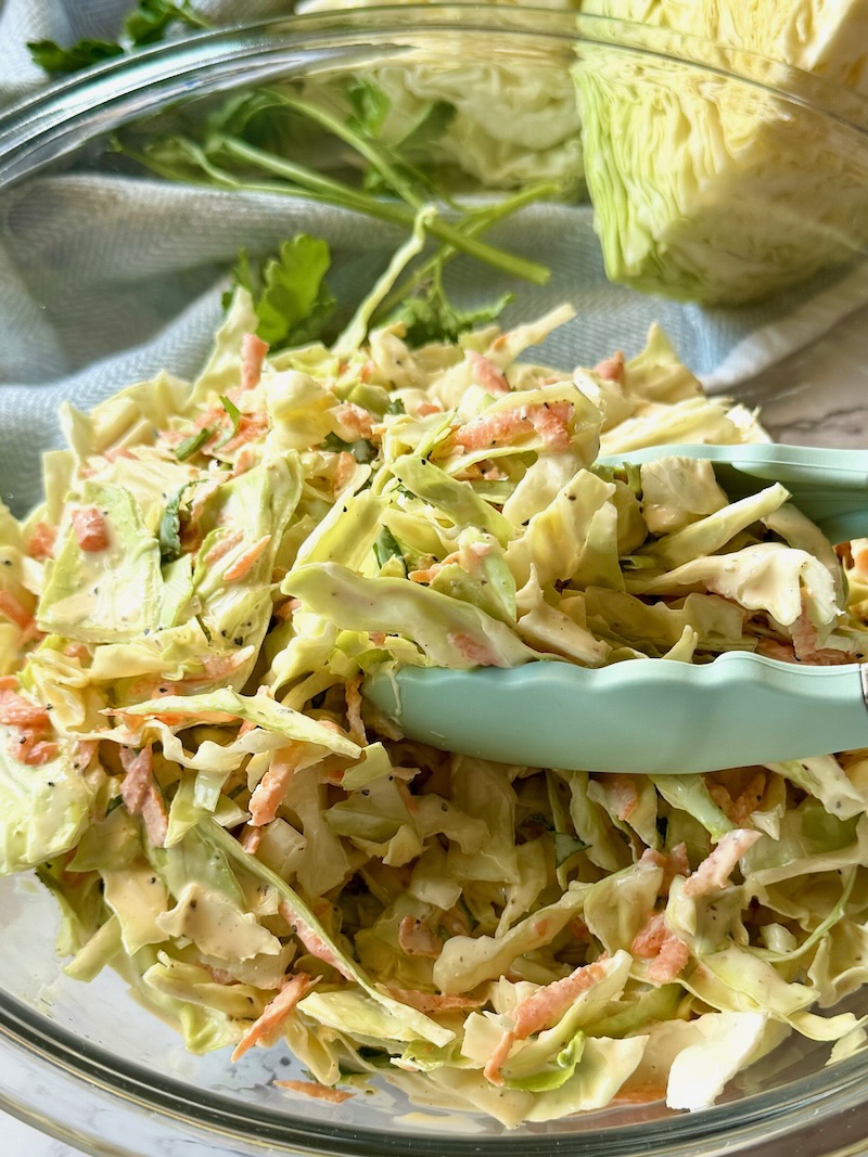 best creamy coleslaw in a serving bowl with tongs