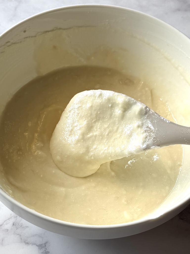 Cream cheese, powdered sugar, and vanilla extract combined in a bowl.