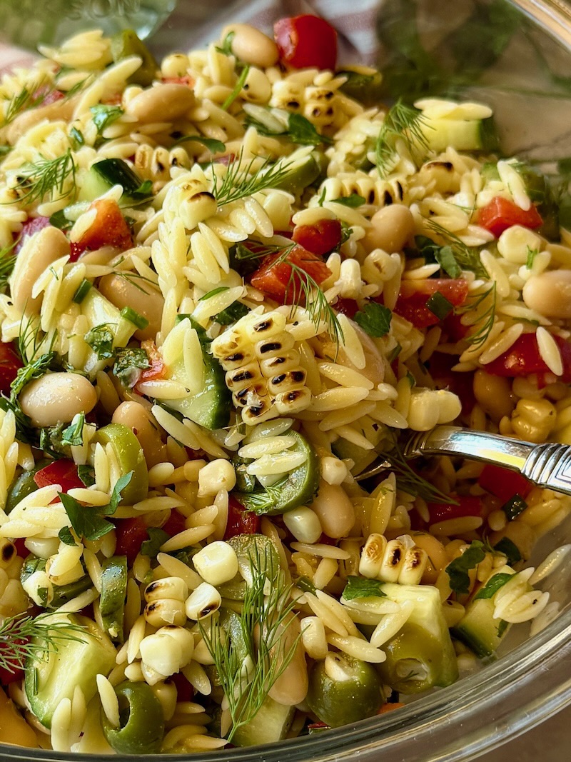Summer glow orzo salad with a serving spoon.