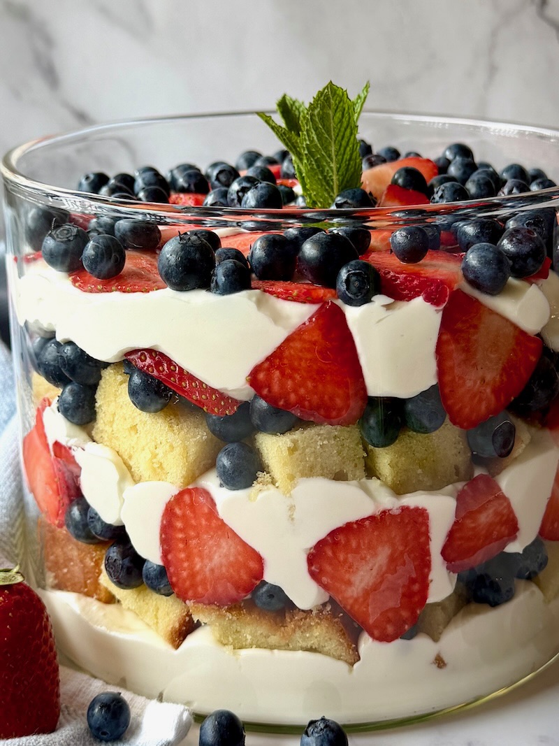 Berry trifle layered in clear bowl and topped with mint.