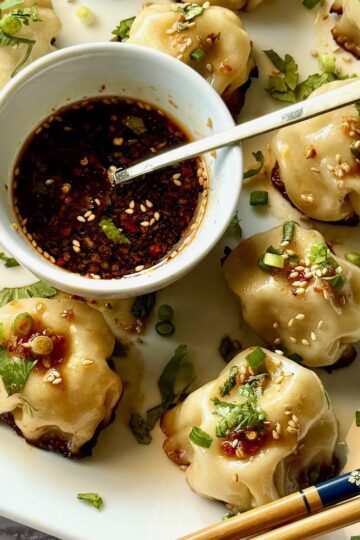 Chicken dumplings with a small bowl of dipping sauce.